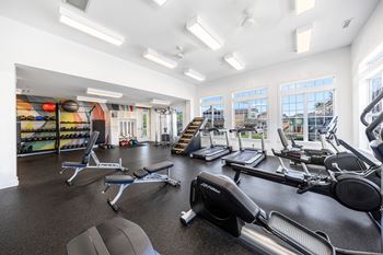 A gym with a variety of equipment including treadmills, weights, and exercise machines.